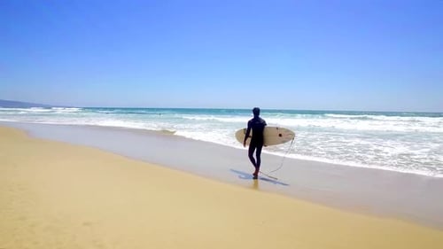 Surfer Walking Down The Beach Tracking Shot
