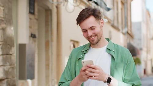 Happy Man Using Smartphone Typing Texting Social Media Application Messages Email on City Street