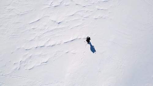 Aerial drone view of solo hiker walking in the mountains during the winter.