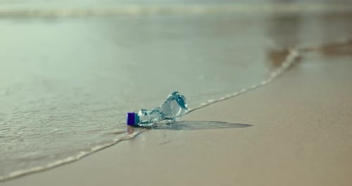 Bottle, beach and waste with pollution of recycle plastic, global warming or hazard on ocean coast