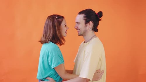 Romantic Couple Smiling and Embracing on Orange Background