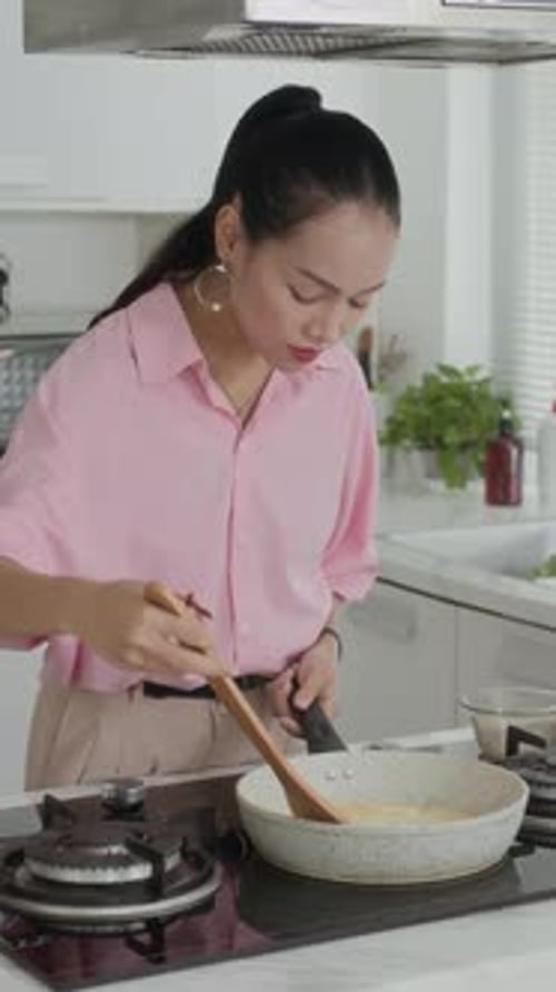 Woman Cooking in Kitchen With Frying Pan and Spatula