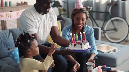 Family celebrates birthday with cake and candles at home