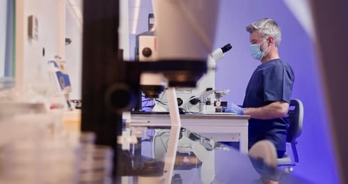 Männlicher Forscher mit Schutzmaske analysiert eine Probe, die in eine