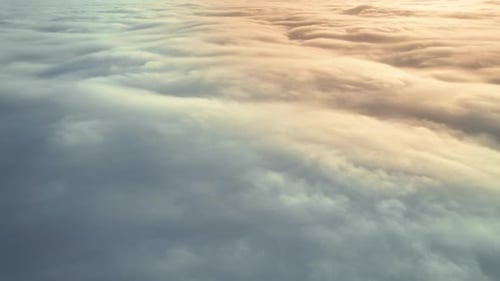 Aerial view from a drone flying above the lush clouds reflecting the sunlight