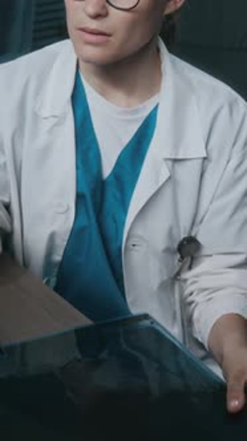 Vertical of Female Radiologist Reviewing X-ray Pictures in Medical Office