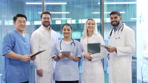 Portrait of group of smiling doctors standing in hospital clinic office looking at camera. Team
