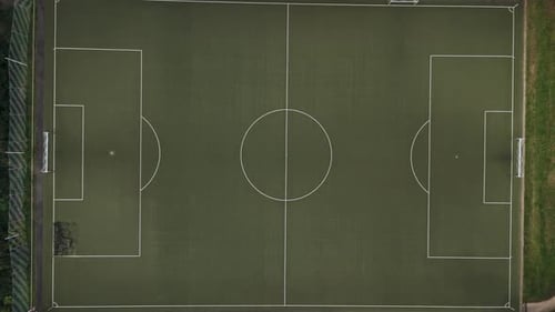 Top Down View of an empty, green football field in the middle of the forest, Drone Footage