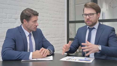 Businessmen Discussing Charts and Graphs in Office Meeting