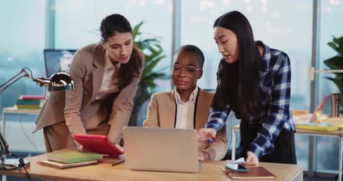 Three Women Collaborate at Desk in Bright Modern Office