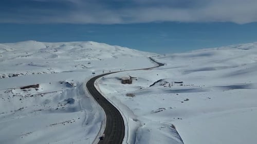 Luftaufnahme der kurvenreichen Autobahn durch schneebedeckte Berge