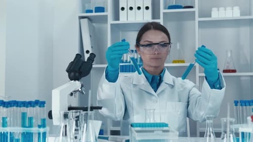Woman in Lab Coat Examining Test Tubes