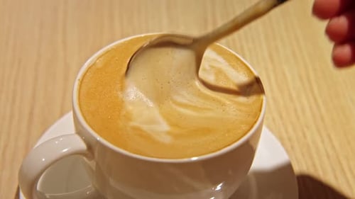 Stirring Latte with a Spoon in the Mug