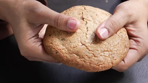 Hands Breaking a Chocolate Chip Cookie in Half