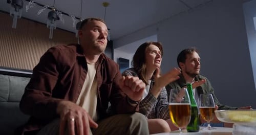 Three Friends Sitting Together in a Living Room Watching Television with Changing Emotions From
