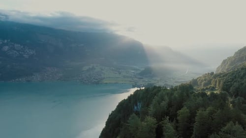 Drone flight over a beautiful Swiss alpine lake. The drone flies above the valley forest to reveal t