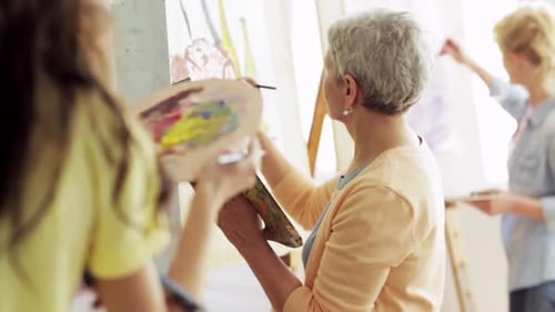 Art School, Creativity And People Concept - Group Of Students With Easels, Paintbrushes And Palet...