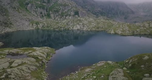 Aerial shot of an lake of mountains surrounded by nature in a magical, relaxing and green place.