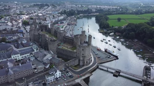 Ancient Caernarfon castle Welsh harbour town aerial view medieval waterfront landmark high lowering