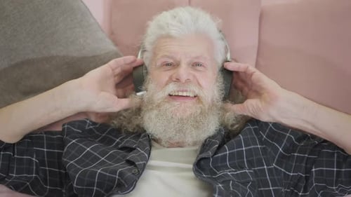 Top View Portrait of Cheerful Relaxed Senior Man in Headphones with Toothy Smile Listening to Music