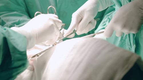 Close up. Gloved hands of surgeon and medical team carefully using forceps and clamps while