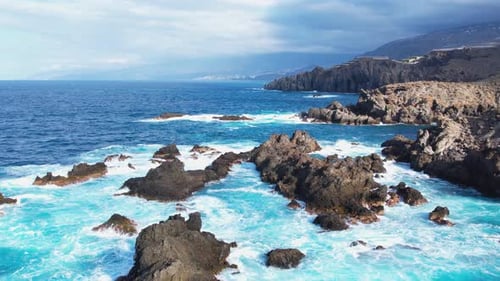 Bird's Eye View of Ocean Waves Crashing Against Stone Cliffs on Tenerife Island