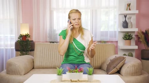 Frustrated Woman Talking on Mobile Phone at Home