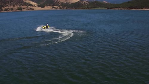 Man rides personal watercraft on peaceful lake enjoying summer vacation