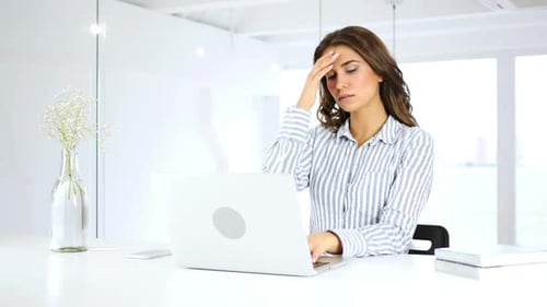 Woman working at desk experiencing a headache