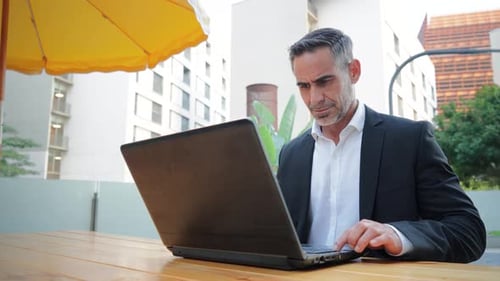 Mature Business Man Working with a Laptop Outside Sitting at Coffee Shop Handsome Executive Male