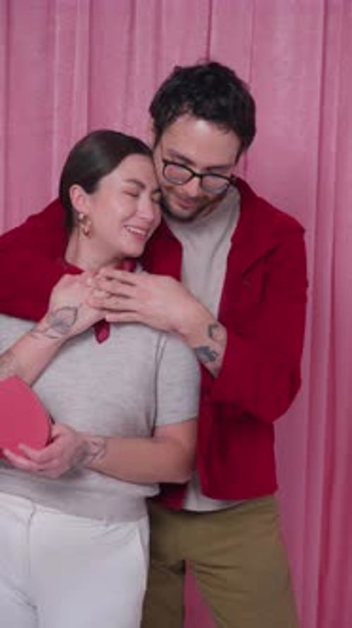 Affectionate Couple Embracing with Heart Box in Valentine Photo Booth