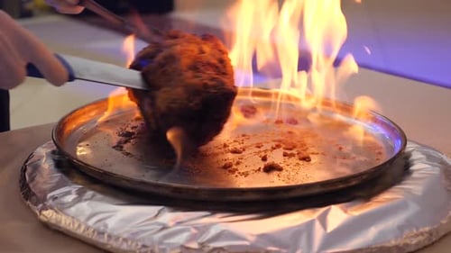 Large Piece of Meat on Fire Being Turned