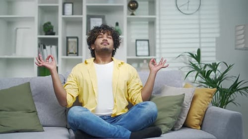 Man Meditating on Sofa in Bright Living Room