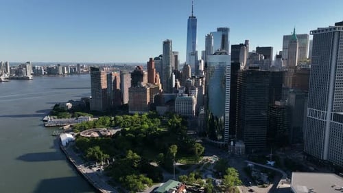 An aerial view of lower Manhattan and the Hudson River on a sunny day with blue skies. The drone cam
