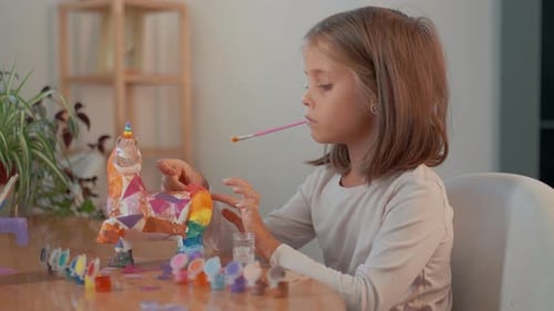 Little Girl Painting and Decorating Unicorn Figurine at Home