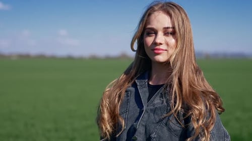 Attractive Young Woman Stands in Green Field