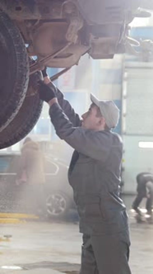 Mechanic Working on a Car Lifted in Auto Shop