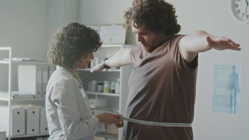 Médecin mesurant la circonférence corporelle d'un homme en surpoids et donnant des conseils
