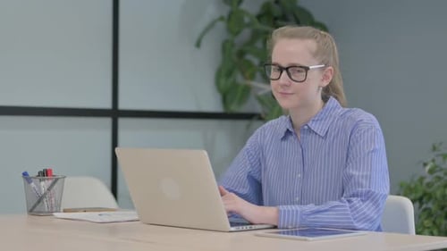 Cheerful Woman Working at Desk Giving Thumbs Up