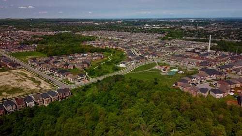 Aerial drone video flying forward over houses, parks and trees in the suburbs on a sunny day