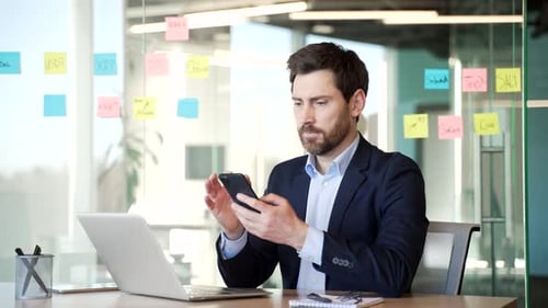 Worried Man Working on Phone in Modern Office