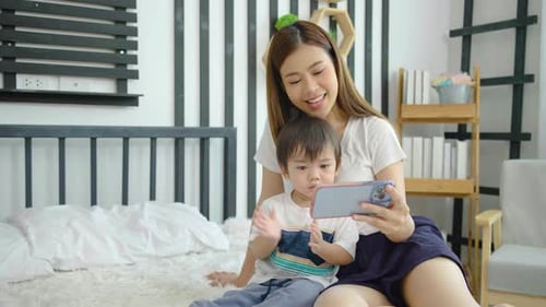 Mother and Child Using Mobile Phone on Bed