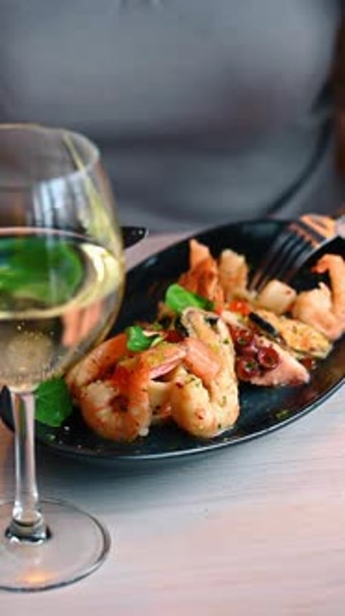 Close up of seafood plate with blurred white wine glass.