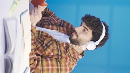 Young Adult Studying with Headphones and Notebooks