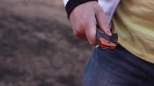Knife crime on a street. A man pulls out a flick knife to attack or threaten his victim