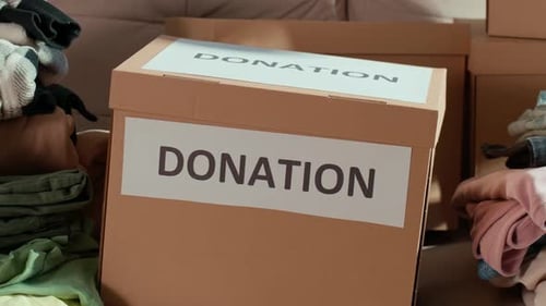 Für die Spende vorbereitete Kleidung in einer Pappschachtel