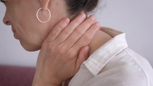 Frau mit schmerzhaftem Gesicht, das den Hals berührt