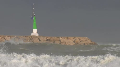 Crashing waves and stormy seas on harbor wall