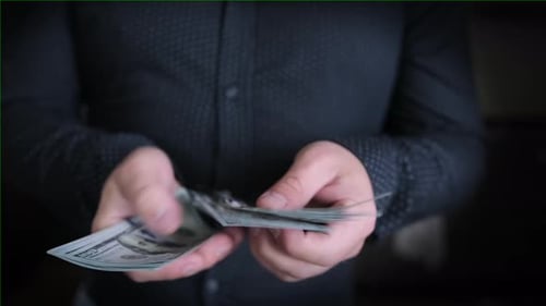 On black isolated background close up, businessman in a shirt counts money