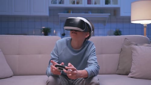 Child Playing VR Game on Sofa at Night